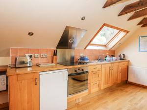 uma cozinha com armários de madeira, um lavatório e uma janela em Larch Cottage em Weem