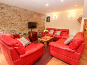 a living room with two red couches and a tv at Bugaboo Cottage in Weem