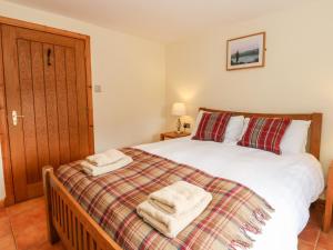 a bedroom with a bed with two towels on it at Larch Cottage in Weem