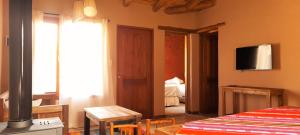 a bedroom with a bed and a television on the wall at Tierra Quebrada Cabañas in Purmamarca