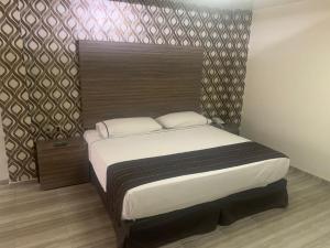 sypialnia z dużym łóżkiem z drewnianym zagłówkiem w obiekcie Motel Pedregal Suites w mieście San Juan del Río