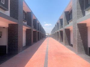 an empty hallway of a building with a red brick sidewalk at Motel Pedregal Suites in San Juan del Río