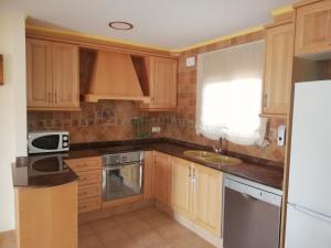 a kitchen with wooden cabinets and a sink and a refrigerator at Casa Rural Los Pineros in Montán