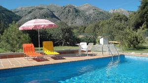 drie stoelen en een parasol naast een zwembad bij Granada 003 in Alhama de Granada