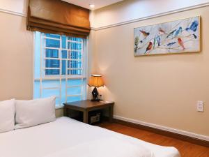 a bedroom with a bed and a table and a window at Good For You Hotel in Ho Chi Minh City
