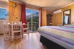 a bedroom with a bed, chair, table and window at B&B y Cabañas Cerro Castillo in Villa Cerro Castillo