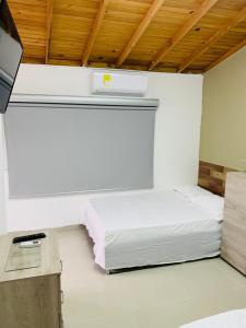 Habitación pequeña con cama y TV. en Casa campestre los cerezos, en Santa Marta