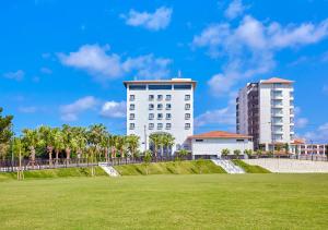 un edificio blanco frente a un campo verde en Hotel Yugaf Inn Okinawa, en Nago