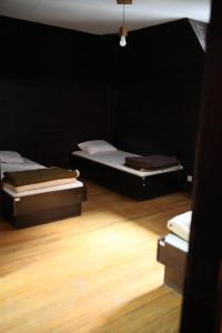 two beds in a black room with wooden floors at Tarweek - Mountain House 