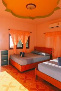 2 camas en una habitación con paredes de color naranja en J.B.Hut Bungalows, en Haad Yao