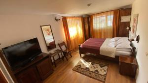 a bedroom with a bed and a flat screen tv at Pensiunea Cerbul Carpatin in Bran