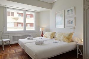 una camera da letto con un grande letto bianco e una finestra di Iraun - Basque Stay a San Sebastián