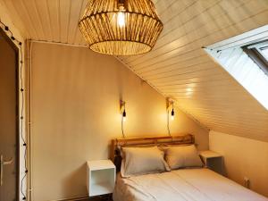 een slaapkamer met een bed en een kroonluchter bij Lacs de l'eau d'heure Chez Oma in Cerfontaine