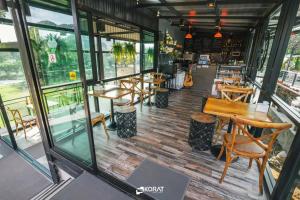 um restaurante com mesas e cadeiras de madeira e janelas em The Piano Resort Khaoyai em Mu Si