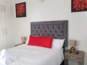 Schlafzimmer mit einem großen Bett und einem roten Kissen in der Unterkunft izuba lodge in Kapstadt