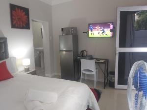 izuba lodge في كيب تاون: غرفة نوم مع سرير وتلفزيون على الحائط