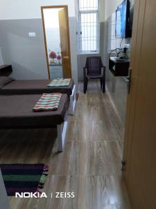 um quarto com duas camas e uma cadeira e uma televisão em TKK Residency em Vellore