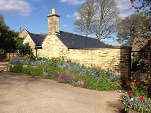 a brick house with a flower garden in front of it at Courtyard Cottage in Stroud
