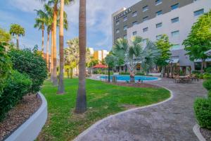 a park with palm trees and a hotel at Hotel Lucerna Hermosillo in Hermosillo