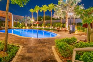 una piscina con palme in un resort di Hotel Lucerna Hermosillo a Hermosillo