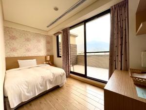 a bedroom with a bed and a large window at 兩腳詩集綠活學旅 l 全自助入住平日旅館 l in Jiji