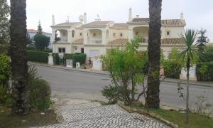 une grande maison blanche avec des arbres en face d'une rue dans l'établissement Votre appartement a Portimao, à Portimão