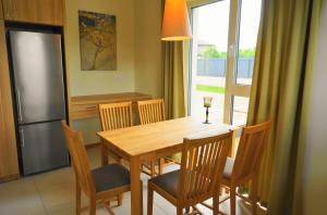 une cuisine avec une table en bois avec des chaises et un réfrigérateur dans l'établissement Smėlio Vila Apartments, à Palanga