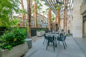 eine Terrasse mit Tischen, Stühlen und Palmen in der Unterkunft Hotel Lucerna Mexicali in Mexicali