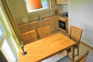 une petite cuisine avec une table et des chaises en bois dans l'établissement Smėlio Vila Apartments, à Palanga 29 autres photos