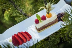 un trozo de pastel y fresas en un plato blanco en Hotel Landgasthof Lärchenwald en Collepietra