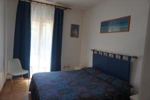 a bedroom with a bed and a chair and a window at Casa Adriana in Alghero