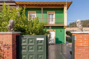 a green garage door in front of a house at Casa entre "Mar y Montaña" centro de Cantabria, terraza, ajardinada, amplia y luminosa, hasta 10 personas in Puente San Miguel