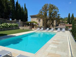 a swimming pool with chairs and a house at Villa La Petraia in Panzano