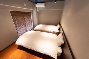 two beds in a small room with a window at NIYS apartments 07 type in Tokyo