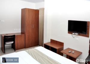 1 dormitorio con 1 cama, escritorio y TV en Hotel Mayo, en Wayanad