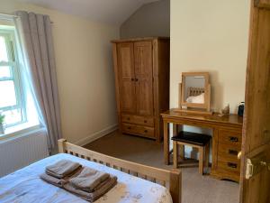 1 dormitorio con cama, tocador y espejo en River Cottage en Conwy