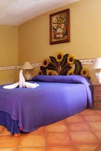 Dormitorio con cama morada con girasoles en la pared en Hacienda Del Caribe Hotel, en Playa del Carmen