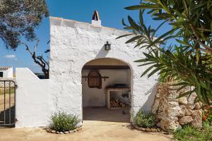 a white building with an archway in a yard at Son Camaro in Ciutadella