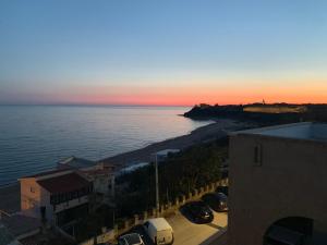 um pôr do sol sobre o oceano com carros estacionados na praia em La Rosa Hotel - Selinunte em Marinella di Selinunte