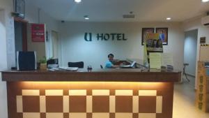 Un uomo seduto al bancone di un hotel in una hall di U HOTEL a Skudai