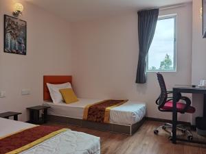 een slaapkamer met 2 bedden, een bureau en een stoel bij MORNINGS HOTEL in Sungai Petani