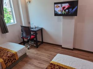 MORNINGS HOTEL في سونغاي بيتاني: غرفة مع سرير ومكتب مع تلفزيون على الحائط