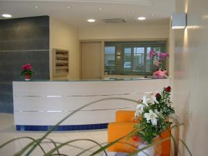 una hall con una sedia arancione e un bancone con fiori di Hotel Bologna a Lignano Sabbiadoro