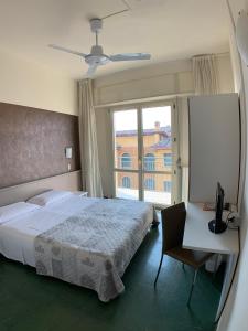 a bedroom with a bed and a desk and a window at Hotel Sorriso in Brenzone sul Garda