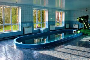 a swimming pool in a room with windows and a slide at Три Брати in Grebenov