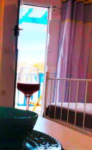a glass of wine sitting on a table next to a door at Salty Kisses and Sandy Toes in Firopótamos