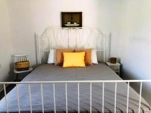 a white bed with an orange pillow on it at Salty Kisses and Sandy Toes in Firopótamos