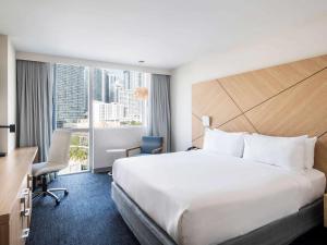 a hotel room with a bed, chair and a window at Novotel Miami Brickell in Miami