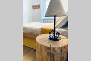 a lamp on a wooden table next to a bed at Appartamento Dolomella in Fai della Paganella