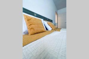 a bedroom with a large white bed with gold pillows at Appartamento Dolomella in Fai della Paganella